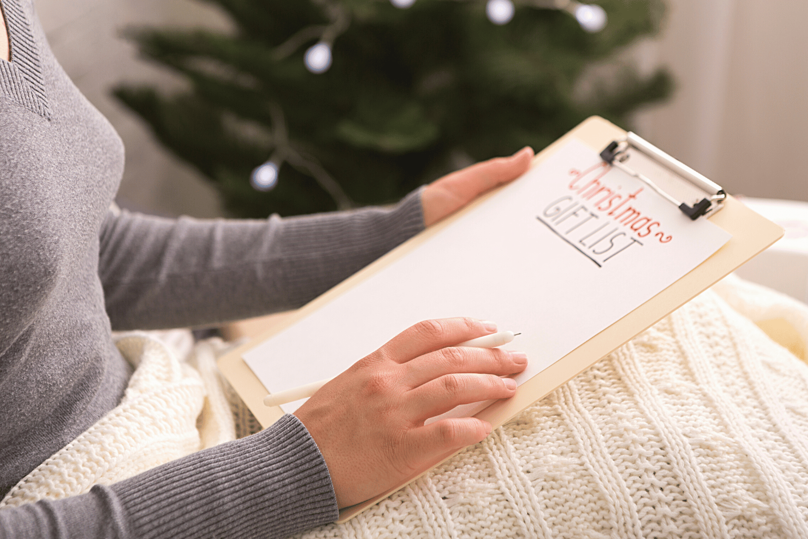 Image featuring a woman diligently writes her Christmas gift list on a clipboard, carefully planning her holiday shopping