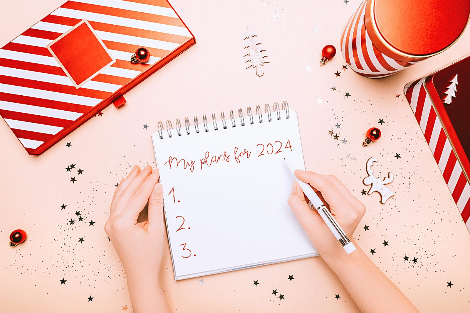 Image of a notebook that has "My Plans for 2024" written on it accompanied by red and white Christmas boxes