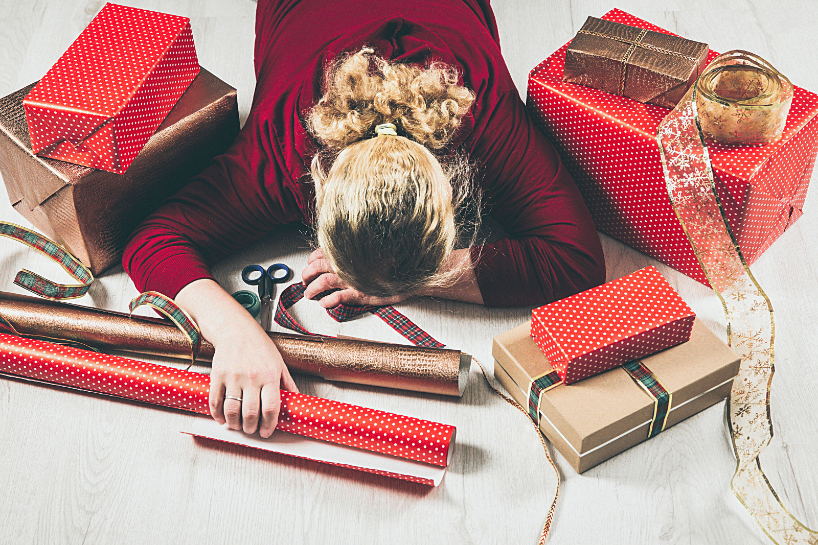 Image featuring a woman housewife tired of wrapping Christmas presents with many gifts around her