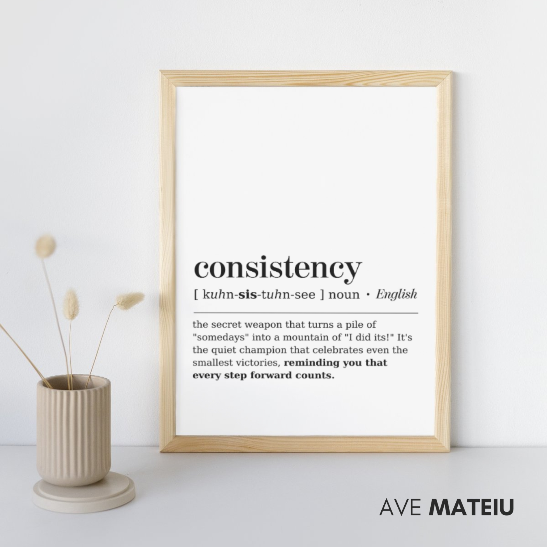 Image featuring a wooden canva frame with the text: Consistency Definition Printable Minimalist Wall Art + the definition of the noun word 'consistency': [ kuhn-sis-tuhn-see ] noun - the secret weapon that turns a pile of "somedays" into a mountain of "I did its!" It's the quiet champion that celebrates even the smallest victories, reminding you that every step forward counts.