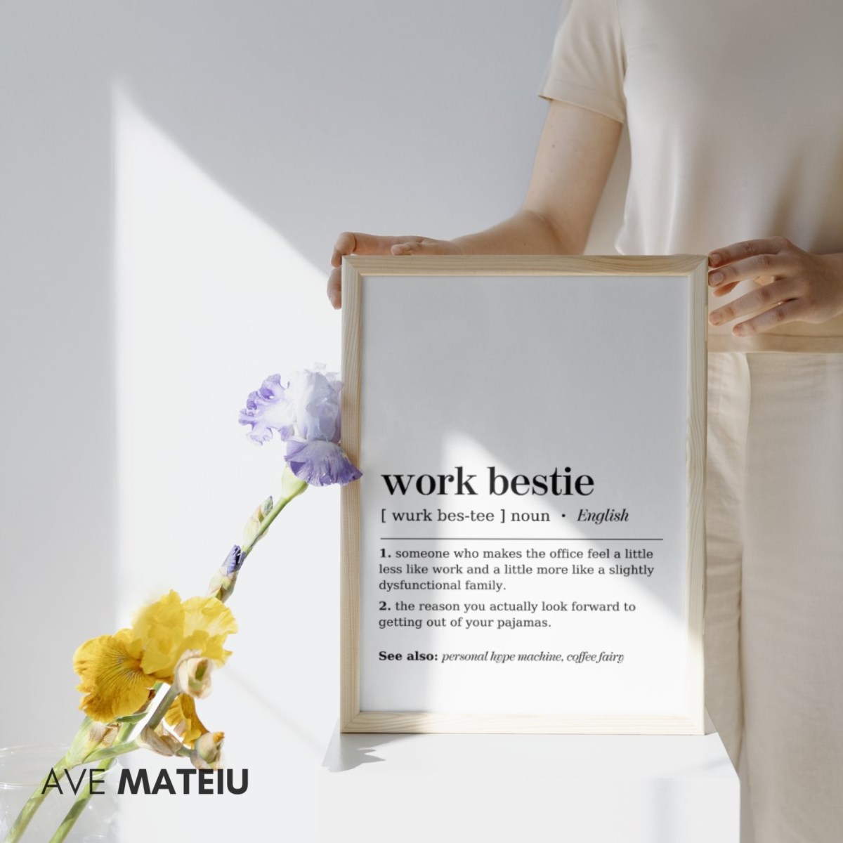 Image featuring a canva frame and flowers with the text: Work Bestie Definition Printable Minimalist Wall Art + the definition of the noun word 'work bestie': [ wurk bes-tee ] noun 1. someone who makes the office feel a little less like work and a little more like a slightly dysfunctional family. 2. the reason you actually look forward to getting out of your pajamas. See also: personal hype machine, coffee fairy